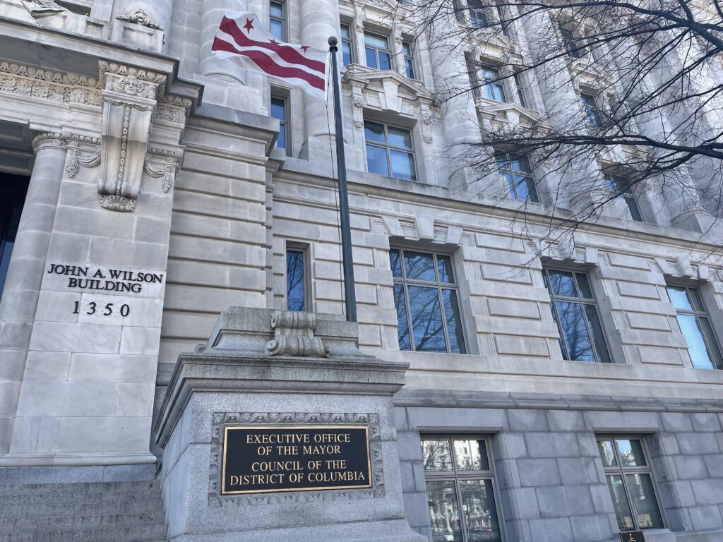 A grey stone building with a plaque designating it as the office of the D.C. Mayor and Council.
