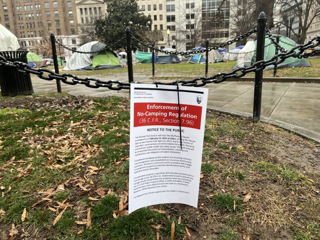A red and white sign hung on a fence announces that the National Park Service will clear the McPherson encampment on Feb. 15.
