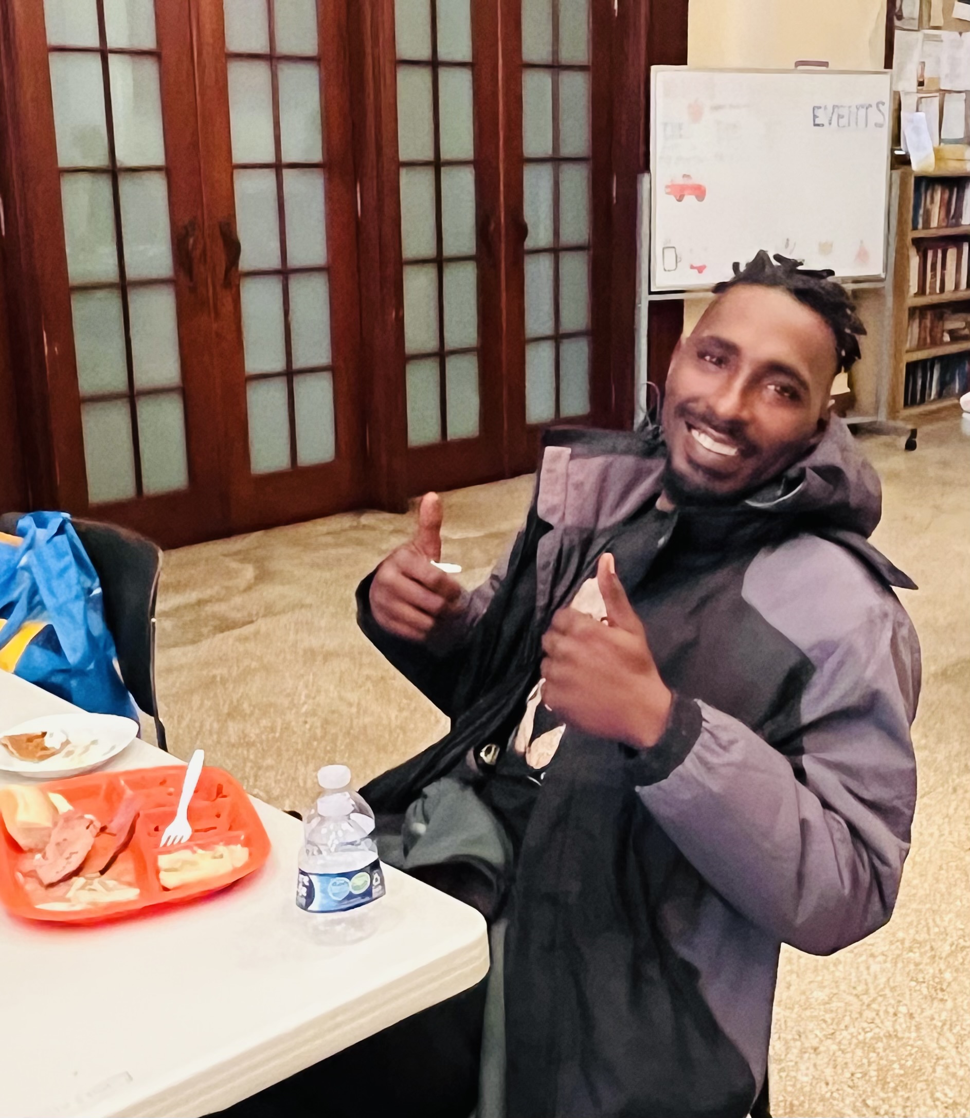 A Black man poses doing a thumbs up.