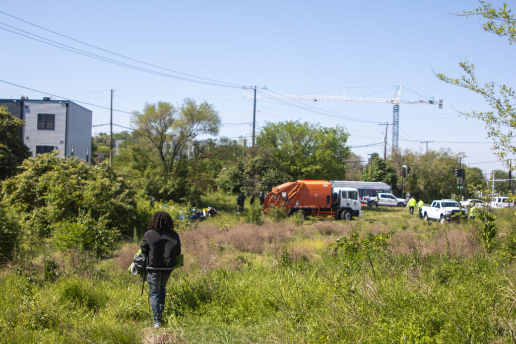 A man carries his belongings across a field towards a truck.