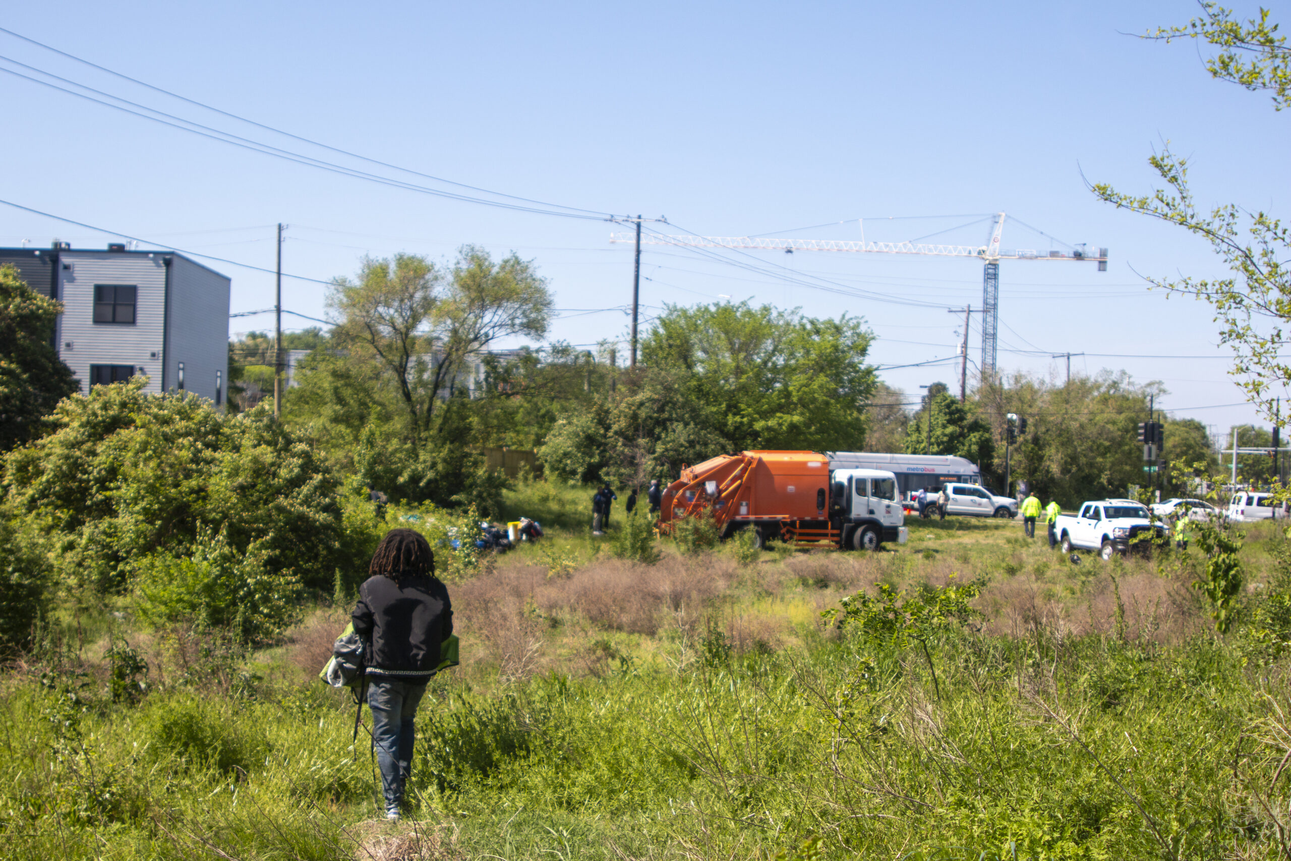 A man carries his belongings across a field towards a truck.