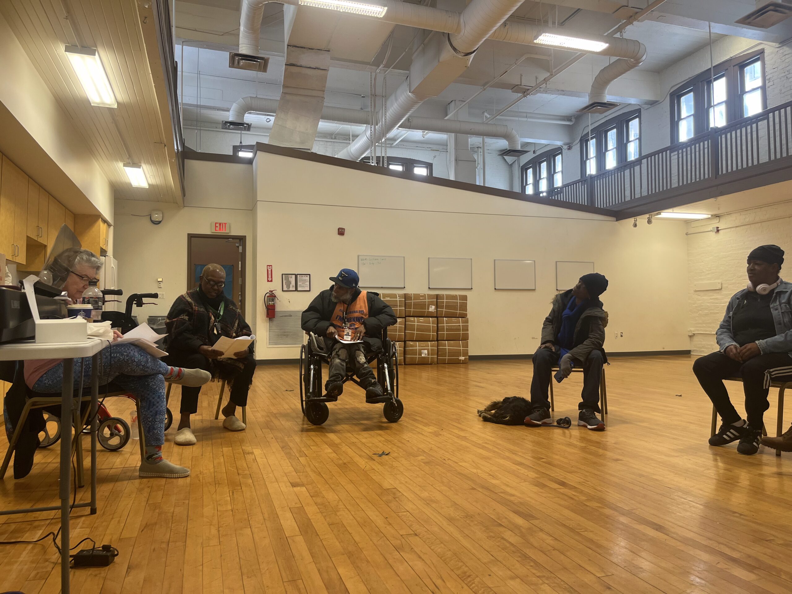 A group of people sit in a circle in a sunny atrium