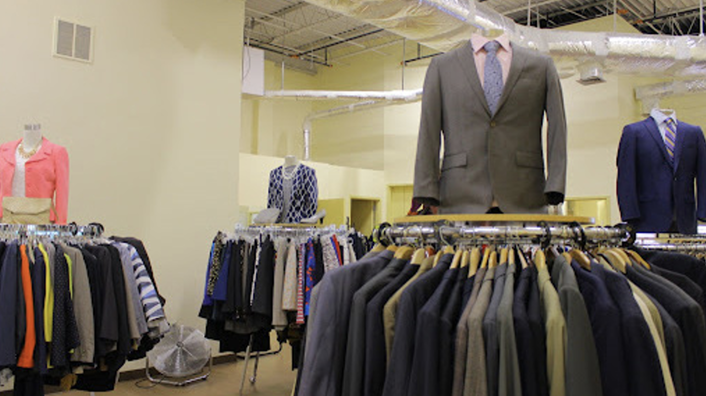 Three circular clothing racks with suits.