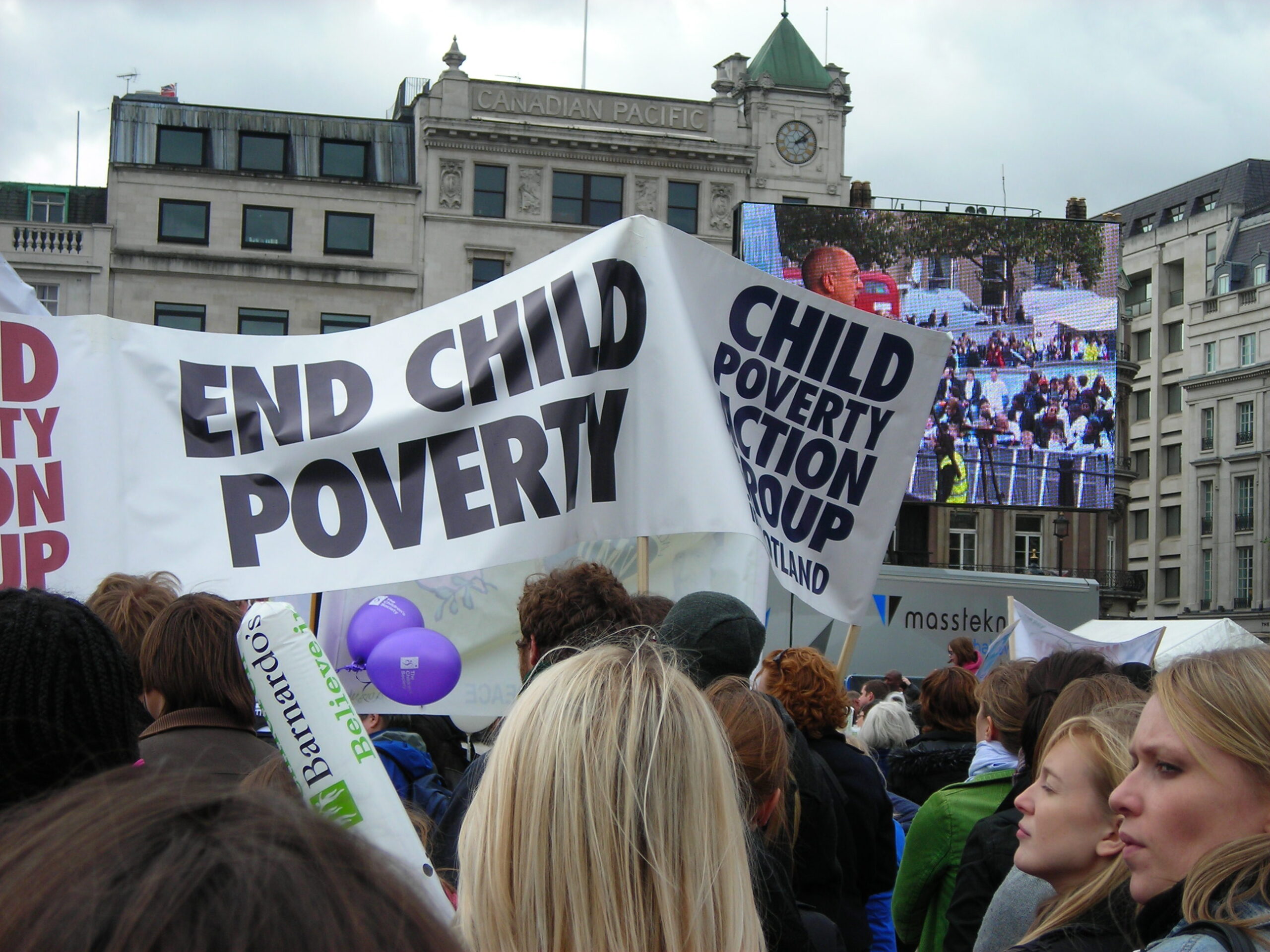 Signs at a rally say end child poverty.