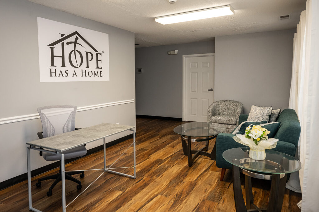 A grey room with chairs and a sign reading "Hope has a home."
