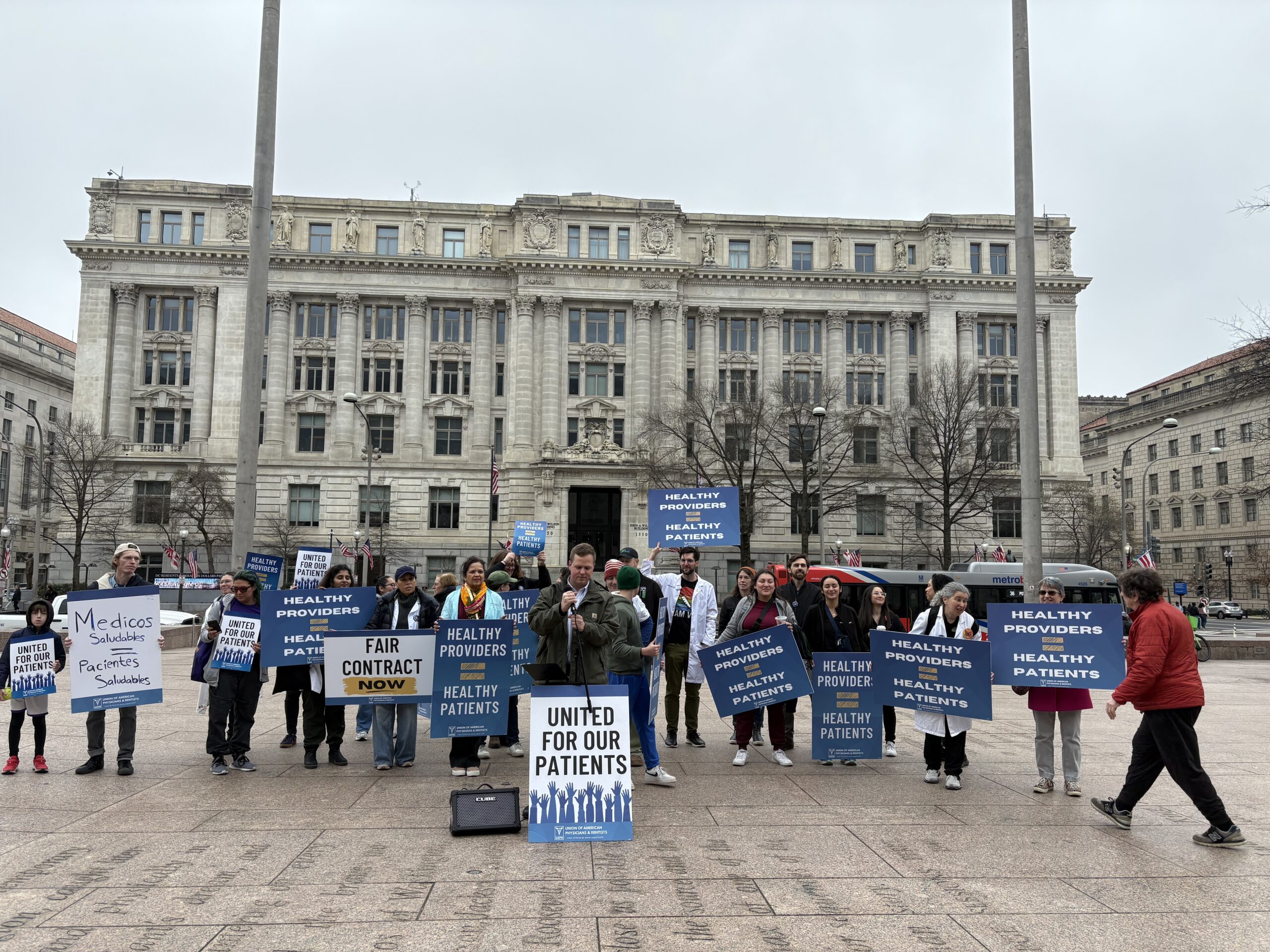 A group of people stand in front of a government building with large signs.