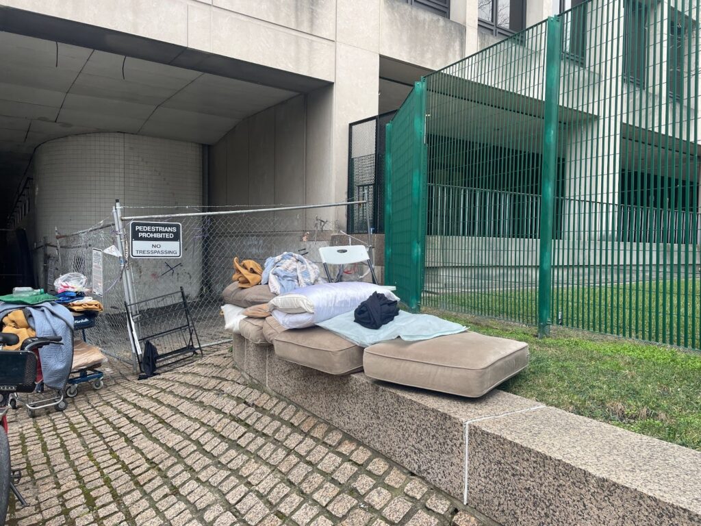A pile of belongings in front of a green fence after the encampment was closed.